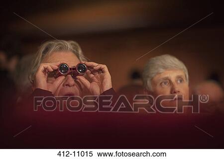 Stock Photography - Close up of man using opera glasses in theater. Fotosearch