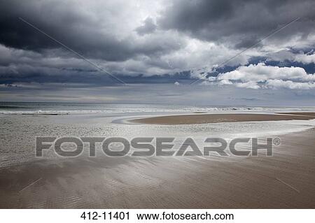 Stock Image - Clouds over beach at low tide. Fotosearch