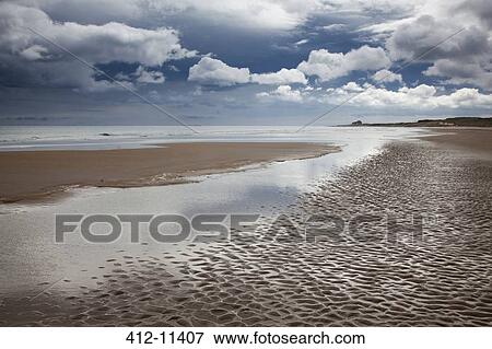 Stock Photo - Clouds over beach at low tide. Fotosearch