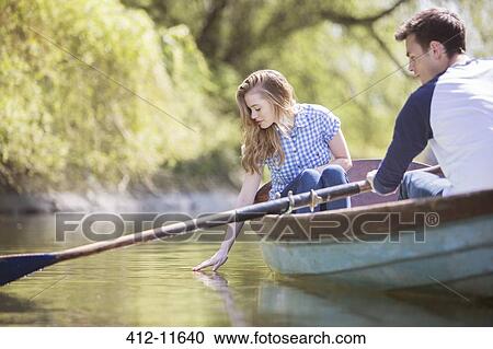 Stock Image - Couple in rowboat on river. Fotosearch