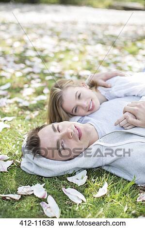 Couple laying in grass outdoors View Large Photo Image Stock Photo - Couple laying in grass outdoors. Fotosearch