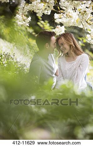 Couple relaxing in grass outdoors View Large Photo Image Stock Photo - Couple relaxing in grass outdoors. Fotosearch