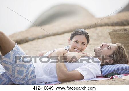 Couple relaxing on beach together View Large Photo Image Stock Photo - Couple relaxing on beach together. Fotosearch
