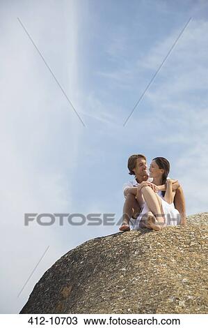 Couple relaxing on rock formation View Large Photo Image Stock Image - Couple relaxing on rock formation. Fotosearch