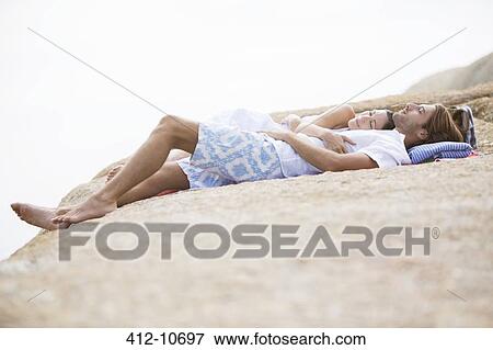 Couple relaxing on rock formation View Large Photo Image Stock Photo - Couple relaxing on rock formation. Fotosearch