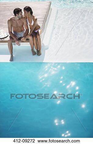 Stock Image - Couple relaxing together at poolside. Fotosearch