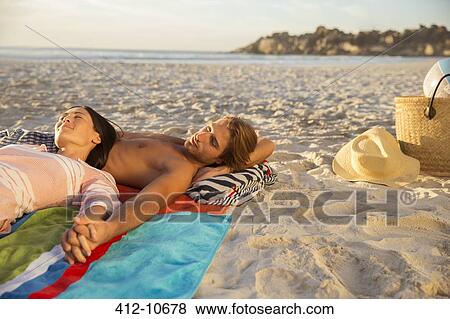 Stock Photo - Couple relaxing together on beach. Fotosearch