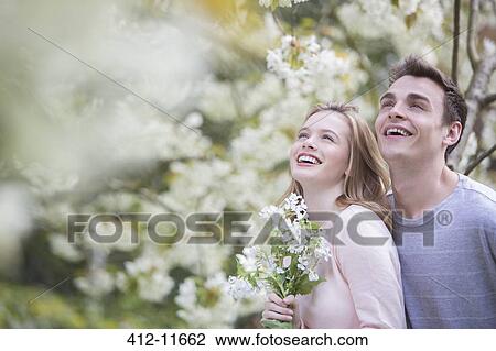 Couple smiling under tree with white blossoms View Large Photo Image Stock Image - Couple smiling under tree with white blossoms. Fotosearch