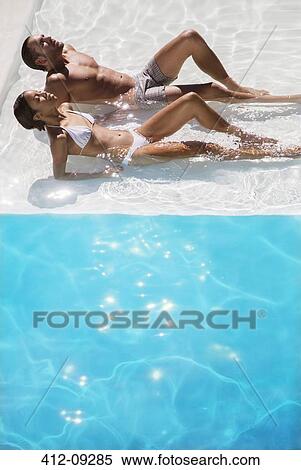 Couple sunbathing in swimming pool View Large Photo Image Stock Photography - Couple sunbathing in swimming pool. Fotosearch