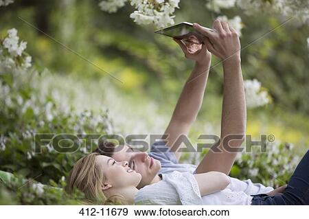 Stock Photo - Couple taking self-portrait with digital tablet in park. Fotosearch