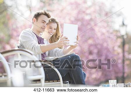 Couple using digital tablet in park View Large Photo Image Stock Image - Couple using digital tablet in park. Fotosearch