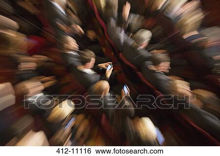 Stock Photograph - Defocused view of men using cell phones in theater audience. Fotosearch