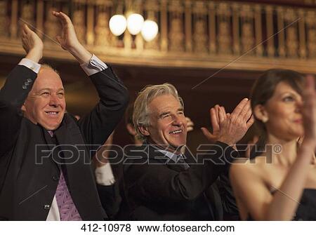 Stock Photo - Enthusiastic men clapping in theater audience. Fotosearch
