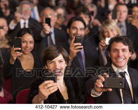 Stock Photo - Enthusiastic theater audience videoing performance with smart phones. Fotosearch
