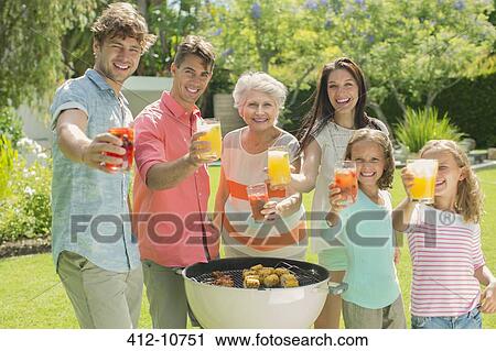 Family barbecuing together in backyard View Large Photo Image Stock Image - Family barbecuing together in backyard. Fotosearch