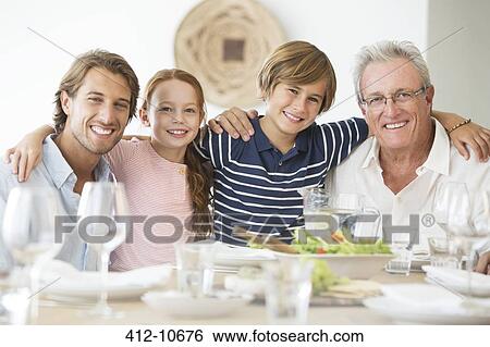 Stock Photograph - Family smiling together at table. Fotosearch