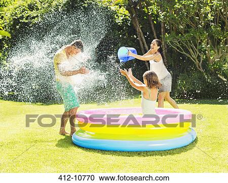 Family tossing water on father in backyard View Large Photo Image Stock Image - Family tossing water on father in backyard. Fotosearch