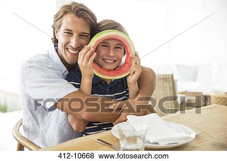 Stock Photo - Father and son playing with food at table. Fotosearch