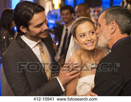 Stock Image - Father kissing bride's cheek at wedding reception. Fotosearch