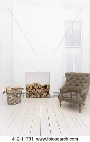 Stock Image - Firewood and armchair in living room. Fotosearch