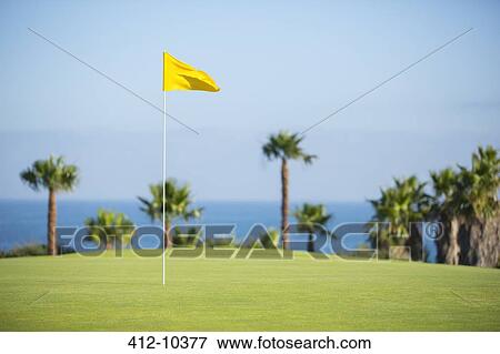 Flag in hole on golf course overlooking ocean View Large Photo Image Stock Photo - Flag in hole on golf course overlooking ocean. Fotosearch