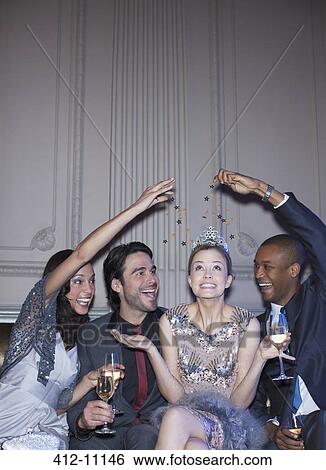 Stock Photograph - Friends reaching over well dressed woman wearing tiara. Fotosearch