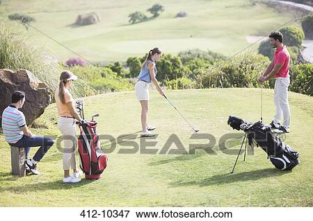 Friends watching woman teeing off on golf course View Large Photo Image Stock Photo - Friends watching woman teeing off on golf course. Fotosearch