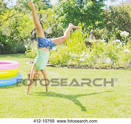 Stock Photo - Girl doing cartwheels in backyard. Fotosearch