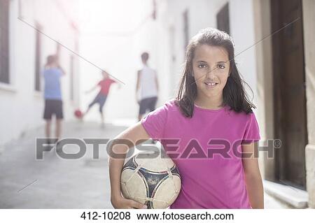 Girl holding soccer ball in alley View Large Photo Image Stock Photo - Girl holding soccer ball in alley. Fotosearch