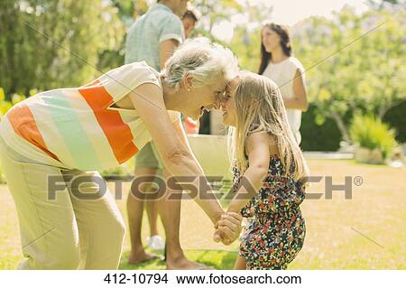Grandmother and granddaughter rubbing noses in backyard View Large Photo Image Picture - Grandmother and granddaughter rubbing noses in backyard. Fotosearch