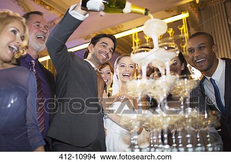Groom pouring champagne pyramid at wedding reception View Large Photo Image Picture - Groom pouring champagne pyramid at wedding reception. Fotosearch