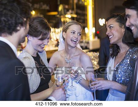 Happy bride drinking champagne with friends at wedding reception View Large Photo Image Stock Photograph - Happy bride drinking champagne with friends at wedding reception. Fotosearch