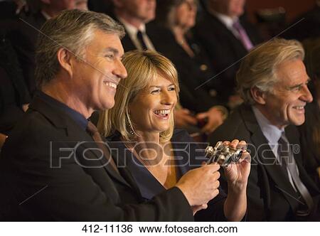 Stock Photograph - Happy couple holding opera glasses in theater audience. Fotosearch