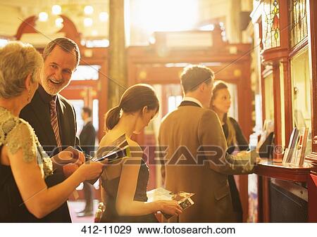 Stock Photo - Happy couple looking at playbill in theater lobby. Fotosearch