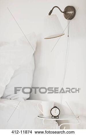 Picture - Lamp and bedside table in white bedroom. Fotosearch
