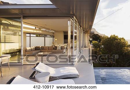 Lounge chairs at poolside of modern house View Large Photo Image Stock Photo - Lounge chairs at poolside of modern house. Fotosearch