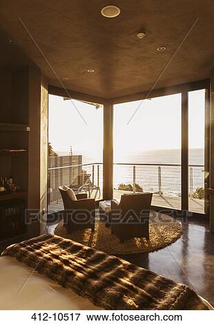 Stock Photo - Luxury bedroom overlooking ocean at sunset. Fotosearch