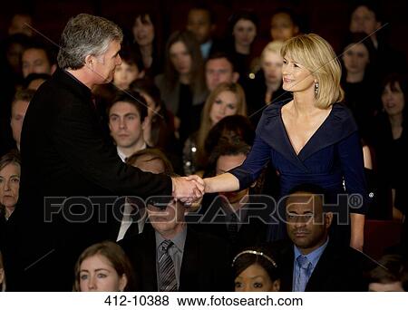 Stock Photo - Man and woman handshaking in theater audience. Fotosearch