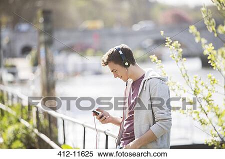 Man listening to headphones outdoors View Large Photo Image Stock Photography - Man listening to headphones outdoors. Fotosearch