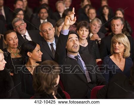 Stock Photography - Man raising hand in theater audience. Fotosearch