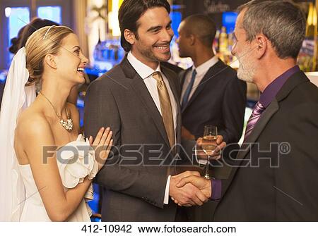 Stock Image - Man shaking hands with groom at wedding reception. Fotosearch