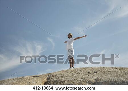 Picture - Man standing on rock formation. Fotosearch