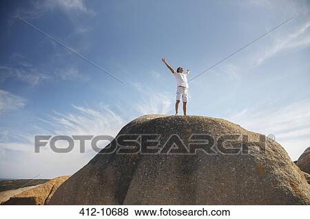 Man standing on top of rock formation View Large Photo Image Stock Photo - Man standing on top of rock formation. Fotosearch