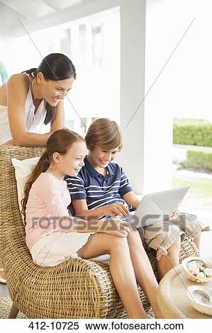 Mother and children using laptop in living room View Large Photo Image Stock Photography - Mother and children using laptop in living room. Fotosearch