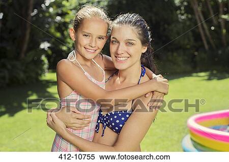 Stock Photography - Mother and daughter hugging in backyard. Fotosearch