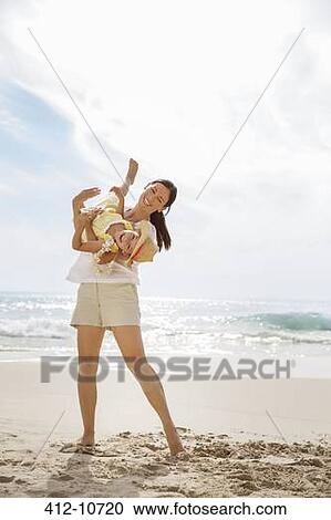 Stock Image - Mother playing with daughter on beach. Fotosearch