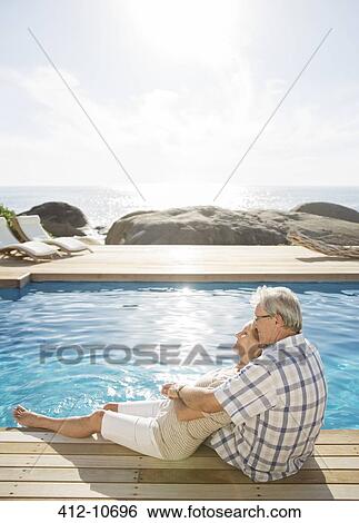 Stock Photograph - Older couple relaxing by pool. Fotosearch