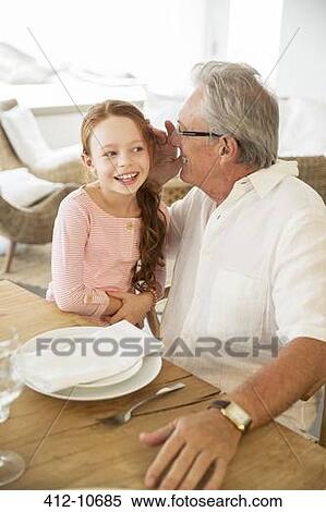 Older man and granddaughter whispering at table View Large Photo Image Stock Photography - Older man and granddaughter whispering at table. Fotosearch