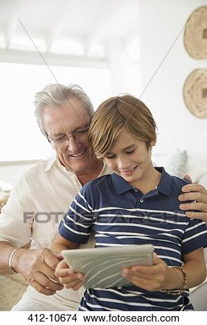 Picture - Older man and grandson using digital tablet. Fotosearch