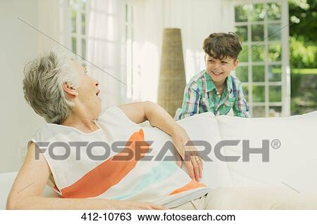 Stock Image - Older woman and grandson playing in living room. Fotosearch